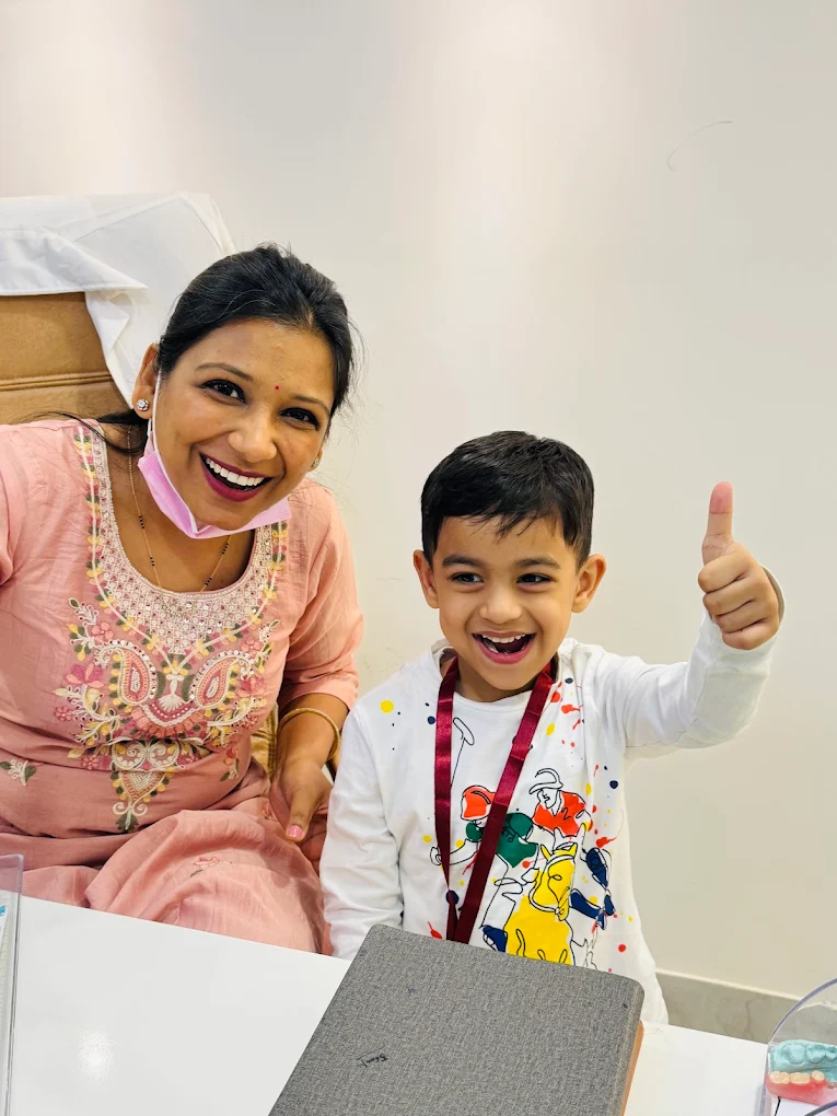 Dr. Anukriti Gupta with a smiling young patient giving a thumbs up